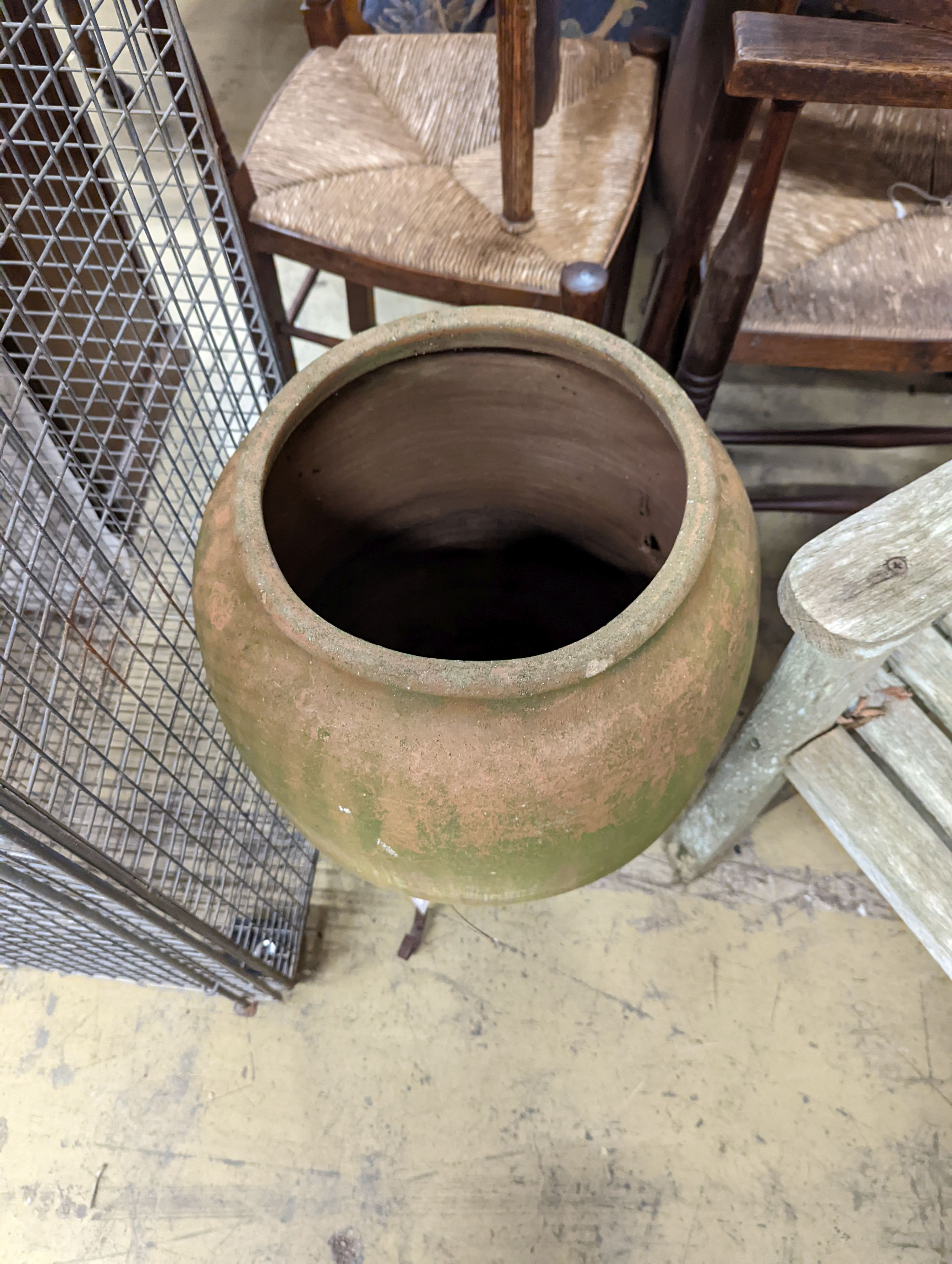 A terracotta garden urn on wrought iron stand. W-38cm, D-38cm, H-68cm.